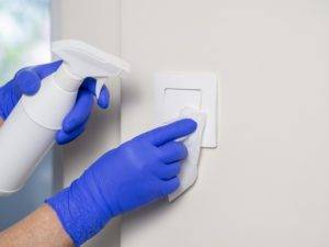 Person With Gloves Disinfecting Light Switches Using Sanitizer